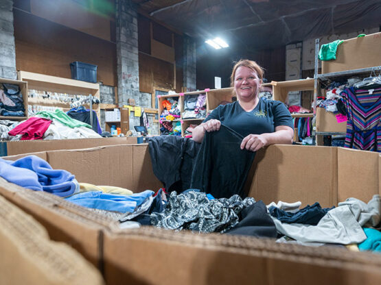 Female worker sorting clothes in Donations Center warehouse